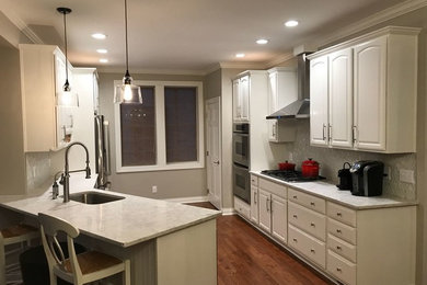 Mid-sized elegant galley dark wood floor and brown floor kitchen photo in Columbus with an undermount sink, raised-panel cabinets, white cabinets, quartzite countertops, white backsplash, glass tile backsplash, paneled appliances, a peninsula and white countertops