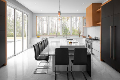 Стильный дизайн: большая кухня в стиле модернизм с стеклянными фасадами, белым фартуком, техникой из нержавеющей стали и островом - последний тренд