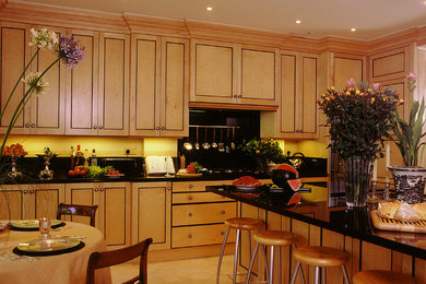 Klassische Wohnküche mit hellbraunen Holzschränken und Küchenrückwand in Schwarz in Sonstige