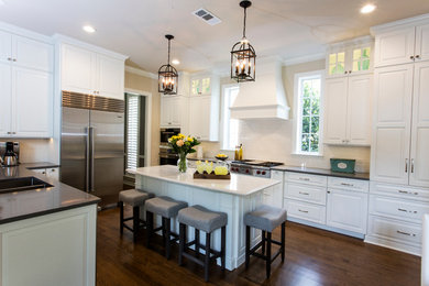 Inspiration for a large transitional u-shaped dark wood floor enclosed kitchen remodel in Dallas with a double-bowl sink, raised-panel cabinets, white cabinets, white backsplash, stainless steel appliances, an island, quartz countertops and subway tile backsplash