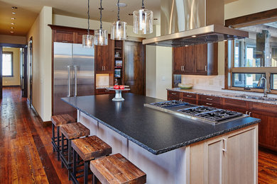 Photo of a medium sized traditional l-shaped kitchen in Other with a submerged sink, shaker cabinets, dark wood cabinets, granite worktops, white splashback, ceramic splashback, stainless steel appliances, dark hardwood flooring, an island and brown floors.