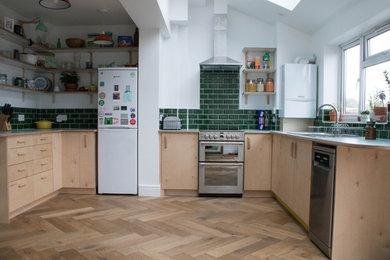 На фото: кухня в современном стиле с плоскими фасадами, светлыми деревянными фасадами, паркетным полом среднего тона и синей столешницей