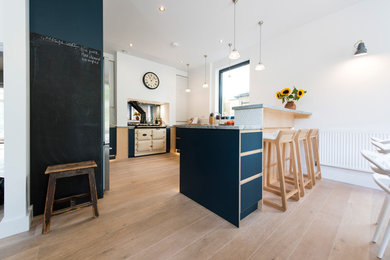 コーンウォールにある広いコンテンポラリースタイルのおしゃれなキッチン (青いキャビネット、亜鉛製カウンター、淡色無垢フローリング) の写真