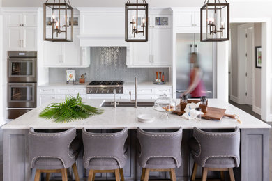 Inspiration for a coastal galley dark wood floor and brown floor kitchen remodel in Tampa with an undermount sink, shaker cabinets, white cabinets, gray backsplash, mosaic tile backsplash, stainless steel appliances, an island and white countertops