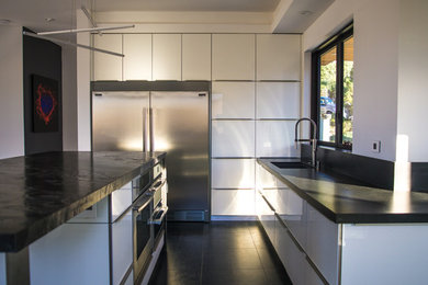 Imagen de cocinas en L moderna grande con armarios con paneles lisos, puertas de armario blancas, encimera de granito, electrodomésticos de acero inoxidable y una isla