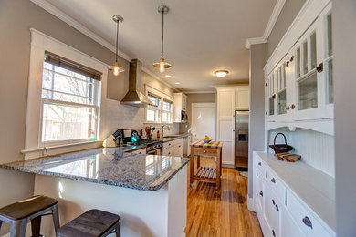 Example of a mid-sized arts and crafts l-shaped medium tone wood floor eat-in kitchen design in Birmingham with an undermount sink, flat-panel cabinets, white cabinets, granite countertops, white backsplash, subway tile backsplash, stainless steel appliances and an island