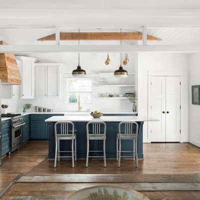 Inspiration for a country l-shaped medium tone wood floor and brown floor open concept kitchen remodel in New Orleans with a farmhouse sink, shaker cabinets, blue cabinets, white backsplash, subway tile backsplash, stainless steel appliances, an island, white countertops and marble countertops