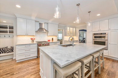 Kitchen - u-shaped dark wood floor and brown floor kitchen idea in Detroit with a single-bowl sink, shaker cabinets, white cabinets, quartzite countertops, white backsplash, ceramic backsplash, stainless steel appliances and an island