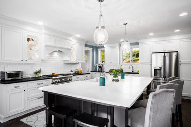 フィラデルフィアにある高級な広いトラディショナルスタイルのおしゃれなキッチン (エプロンフロントシンク、インセット扉のキャビネット、黒いキャビネット、クオーツストーンカウンター、白いキッチンパネル、サブウェイタイルのキッチンパネル、シルバーの調理設備、濃色無垢フローリング、茶色い床、白いキッチンカウンター) の写真