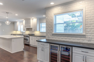 Inspiration for a huge timeless l-shaped dark wood floor eat-in kitchen remodel in Houston with an undermount sink, raised-panel cabinets, white cabinets, marble countertops, white backsplash, subway tile backsplash, stainless steel appliances and an island