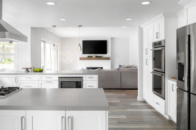 Example of a large trendy u-shaped porcelain tile and gray floor eat-in kitchen design in Los Angeles with a single-bowl sink, shaker cabinets, white cabinets, quartz countertops, white backsplash, porcelain backsplash, stainless steel appliances, two islands and gray countertops