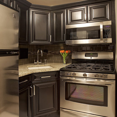 Elegant kitchen photo in New York with an undermount sink, raised-panel cabinets, black cabinets, gray backsplash, subway tile backsplash and stainless steel appliances