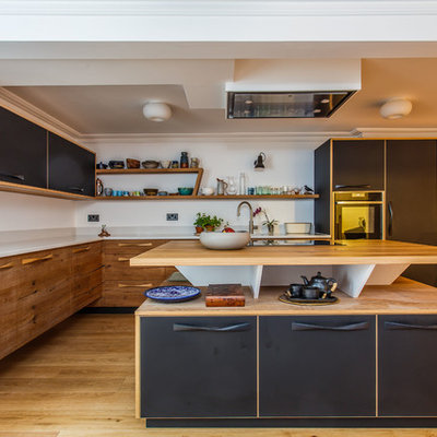 Inspiration for a mid-sized modern l-shaped light wood floor and beige floor kitchen remodel in Sussex with an undermount sink, flat-panel cabinets, medium tone wood cabinets, stainless steel appliances, an island, white countertops and wood countertops