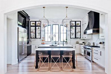 Inspiration for a transitional u-shaped light wood floor and beige floor kitchen remodel in Nashville with white backsplash, stone slab backsplash, stainless steel appliances, an island, white countertops and flat-panel cabinets