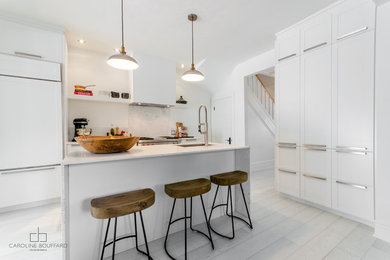 Example of a transitional light wood floor kitchen design in Montreal with an undermount sink, shaker cabinets, white cabinets, marble countertops, white backsplash, stainless steel appliances and an island