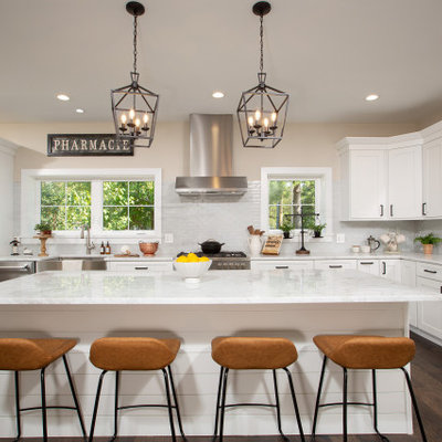 Kitchen - country l-shaped dark wood floor and brown floor kitchen idea in DC Metro with a farmhouse sink, shaker cabinets, white cabinets, white backsplash, subway tile backsplash, stainless steel appliances, an island and white countertops