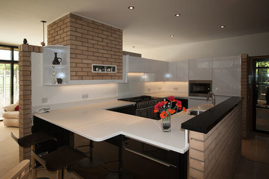 Photo of a modern kitchen in Other with a submerged sink, flat-panel cabinets, white cabinets, quartz worktops, white splashback, glass sheet splashback, stainless steel appliances and slate flooring.