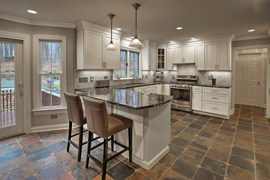 Example of a mid-sized transitional u-shaped slate floor and multicolored floor eat-in kitchen design in New York with an undermount sink, recessed-panel cabinets, white cabinets, granite countertops, gray backsplash, subway tile backsplash, stainless steel appliances and a peninsula