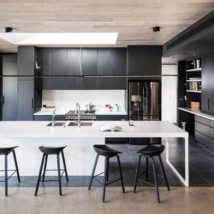 Photo of a large modern kitchen in Melbourne with flat-panel cabinets, quartz benchtops, white splashback, glass sheet splashback, stainless steel appliances, porcelain floors, with island, white benchtop, a double-bowl sink and black floor.