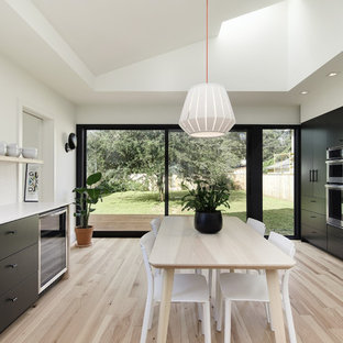 Scandinavian eat-in kitchen designs - Example of a danish light wood floor and beige floor eat-in kitchen design in Austin with flat-panel cabinets, black cabinets, white backsplash, mosaic tile backsplash, stainless steel appliances and white countertops