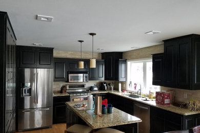 Eat-in kitchen - mid-sized transitional u-shaped medium tone wood floor eat-in kitchen idea in Milwaukee with an undermount sink, raised-panel cabinets, black cabinets, granite countertops, beige backsplash, stone tile backsplash, stainless steel appliances and an island