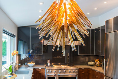 Example of a mid-sized trendy u-shaped ceramic tile enclosed kitchen design in Vancouver with an undermount sink, flat-panel cabinets, black cabinets, marble countertops, black backsplash, glass sheet backsplash, stainless steel appliances and a peninsula