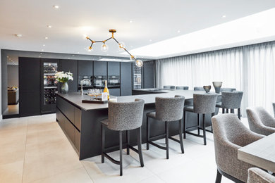 This is an example of a large contemporary u-shaped open plan kitchen in Other with a single-bowl sink, flat-panel cabinets, black cabinets, engineered stone countertops, black splashback, black appliances, porcelain flooring, multiple islands, grey floors and black worktops.