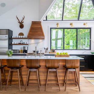 Transitional kitchen remodeling - Example of a transitional l-shaped medium tone wood floor, brown floor and vaulted ceiling kitchen design in Other with an undermount sink, shaker cabinets, black cabinets, white backsplash, stone slab backsplash, stainless steel appliances, an island and white countertops