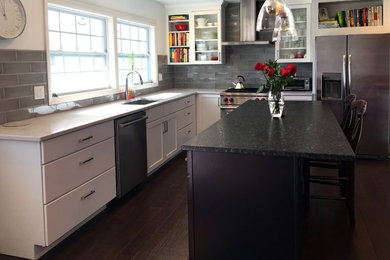 Inspiration for a mid-sized transitional u-shaped dark wood floor and brown floor eat-in kitchen remodel in Chicago with an undermount sink, flat-panel cabinets, white cabinets, granite countertops, gray backsplash, subway tile backsplash, stainless steel appliances, an island and black countertops