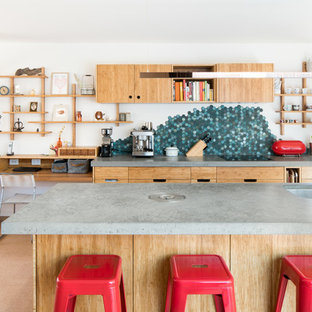 Photo of a mid-sized contemporary u-shaped open plan kitchen in Melbourne with an undermount sink, flat-panel cabinets, light wood cabinets, concrete benchtops, green splashback, stone tile splashback, cork floors, with island, beige floor, panelled appliances and grey benchtop.