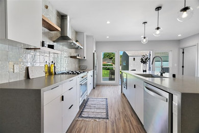Inredning av ett modernt stort grå linjärt grått kök och matrum, med en undermonterad diskho, släta luckor, vita skåp, bänkskiva i kvarts, vitt stänkskydd, stänkskydd i porslinskakel, rostfria vitvaror, vinylgolv, en köksö och brunt golv