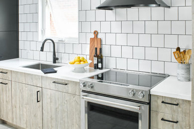 Inspiration for a small modern galley porcelain tile and gray floor enclosed kitchen remodel in Toronto with a single-bowl sink, flat-panel cabinets, light wood cabinets, quartz countertops, white backsplash, subway tile backsplash, stainless steel appliances, no island and white countertops