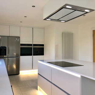 Idee per una cucina minimal di medie dimensioni con lavello integrato, ante lisce, ante bianche, top in quarzite, paraspruzzi bianco, paraspruzzi in granito, elettrodomestici neri, pavimento in vinile, isola, pavimento bianco e top bianco