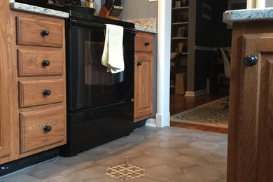 Example of a mid-sized eclectic vinyl floor enclosed kitchen design in Indianapolis with shaker cabinets, medium tone wood cabinets, granite countertops, black appliances and an island