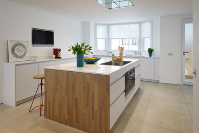 This is an example of a medium sized modern open plan kitchen in London with flat-panel cabinets and an island.