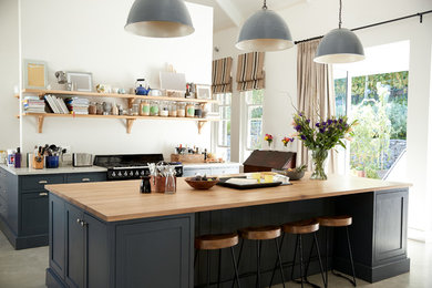 Eat-in kitchen - mid-sized contemporary galley porcelain tile and beige floor eat-in kitchen idea in DC Metro with a farmhouse sink, beaded inset cabinets, blue cabinets, wood countertops, white backsplash, window backsplash, black appliances, an island and beige countertops