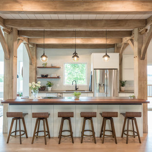 Mid-sized farmhouse open concept kitchen inspiration - Inspiration for a mid-sized cottage light wood floor and beige floor open concept kitchen remodel in Minneapolis with flat-panel cabinets, white cabinets, concrete countertops, an island, an undermount sink, white backsplash, subway tile backsplash, stainless steel appliances and gray countertops