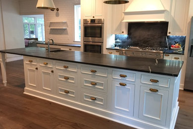 Mid-sized elegant single-wall dark wood floor eat-in kitchen photo in Detroit with an undermount sink, beaded inset cabinets, white cabinets, solid surface countertops, black backsplash, stone slab backsplash, stainless steel appliances and an island