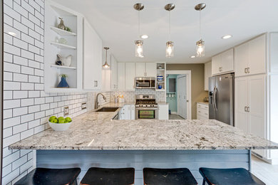 Eat-in kitchen - mid-sized transitional u-shaped porcelain tile and gray floor eat-in kitchen idea in Detroit with a farmhouse sink, shaker cabinets, white cabinets, granite countertops, white backsplash, ceramic backsplash, stainless steel appliances, an island and gray countertops