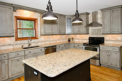 Transitional l-shaped medium tone wood floor kitchen photo in New York with an undermount sink, flat-panel cabinets, gray cabinets, quartz countertops, beige backsplash, porcelain backsplash, stainless steel appliances and an island