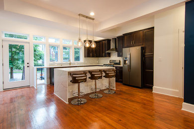 Inspiration for a contemporary medium tone wood floor kitchen remodel in DC Metro with an undermount sink, shaker cabinets, dark wood cabinets, quartz countertops, beige backsplash, glass tile backsplash, stainless steel appliances, an island and white countertops