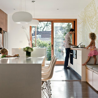 Ejemplo de cocina comedor moderna con electrodomésticos de acero inoxidable, armarios con paneles lisos y puertas de armario de madera en tonos medios