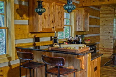 Inredning av ett rustikt mellanstort kök, med en undermonterad diskho, luckor med infälld panel, skåp i mellenmörkt trä, granitbänkskiva, svart stänkskydd, stänkskydd i keramik, rostfria vitvaror och mellanmörkt trägolv
