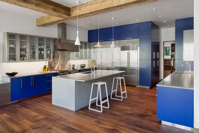 Große Moderne Wohnküche in U-Form mit Unterbauwaschbecken, flächenbündigen Schrankfronten, blauen Schränken, Quarzwerkstein-Arbeitsplatte, Küchengeräten aus Edelstahl, braunem Holzboden und Kücheninsel in Denver