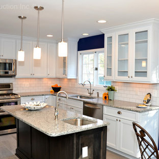 Imagen de cocina comedor en L, clásica, con fregadero bajoencimera, armarios estilo shaker, puertas de armario blancas, encimera de granito, salpicadero blanco, salpicadero de azulejos tipo metro, electrodomésticos de acero inoxidable, suelo de baldosas de cerámica y una isla