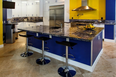 Example of a trendy eat-in kitchen design in Miami with granite countertops, blue backsplash, stone slab backsplash, an undermount sink, flat-panel cabinets, white cabinets, stainless steel appliances and an island
