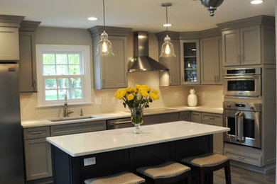 Inspiration for a large transitional l-shaped gray floor and porcelain tile eat-in kitchen remodel in Philadelphia with recessed-panel cabinets, gray cabinets, marble countertops, white backsplash, glass tile backsplash, stainless steel appliances, an island, an undermount sink and white countertops