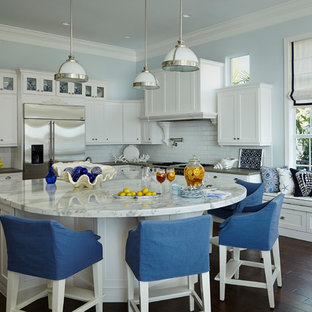 Large coastal open concept kitchen photos - Large beach style l-shaped dark wood floor and brown floor open concept kitchen photo in Miami with white backsplash, subway tile backsplash, an island, shaker cabinets, white cabinets, marble countertops and stainless steel appliances