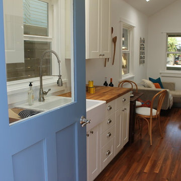 Blue Door Opens Onto Kitchen with White Cabinets