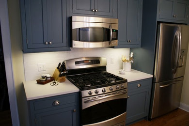 ニューヨークにあるトラディショナルスタイルのおしゃれなキッチン (青いキャビネット、白いキッチンパネル、サブウェイタイルのキッチンパネル、シルバーの調理設備、インセット扉のキャビネット) の写真